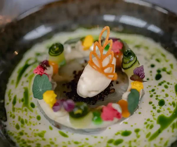Le restaurant Le Solstice à Cassis propose ce carpaccio de noix de Saint Jacques aux fleurs comestibles et légumes croquants.