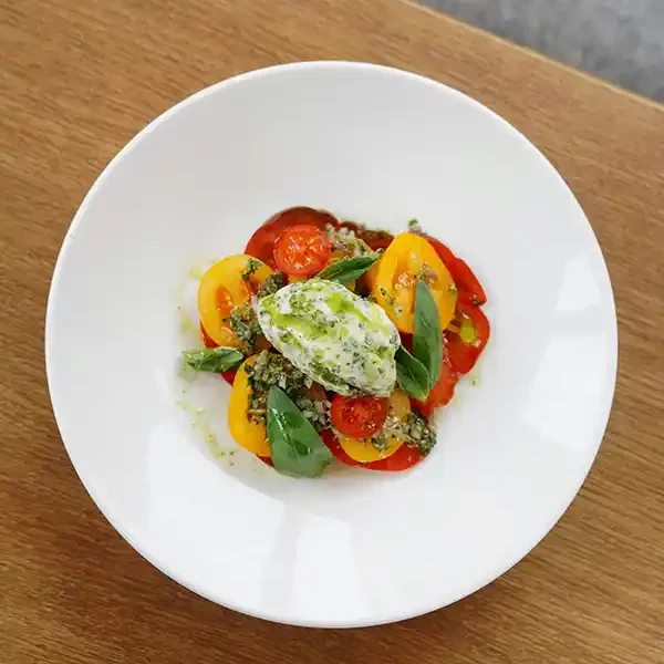 Une burrata crémeuse sur un lit de tomates mûres servie au restaurant Le Solstice à Cassis pour un moment de fraîcheur.